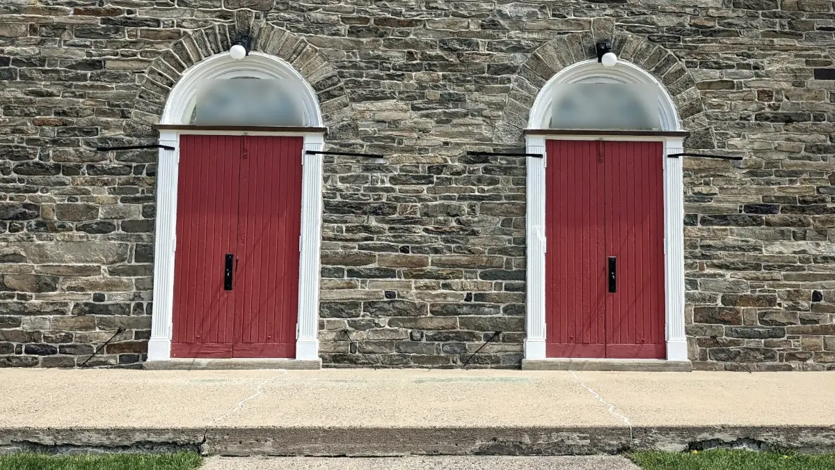 Deux portes rouges identiques côte à côte dans un mur de pierre, symbole d'un choix entre deux démarches