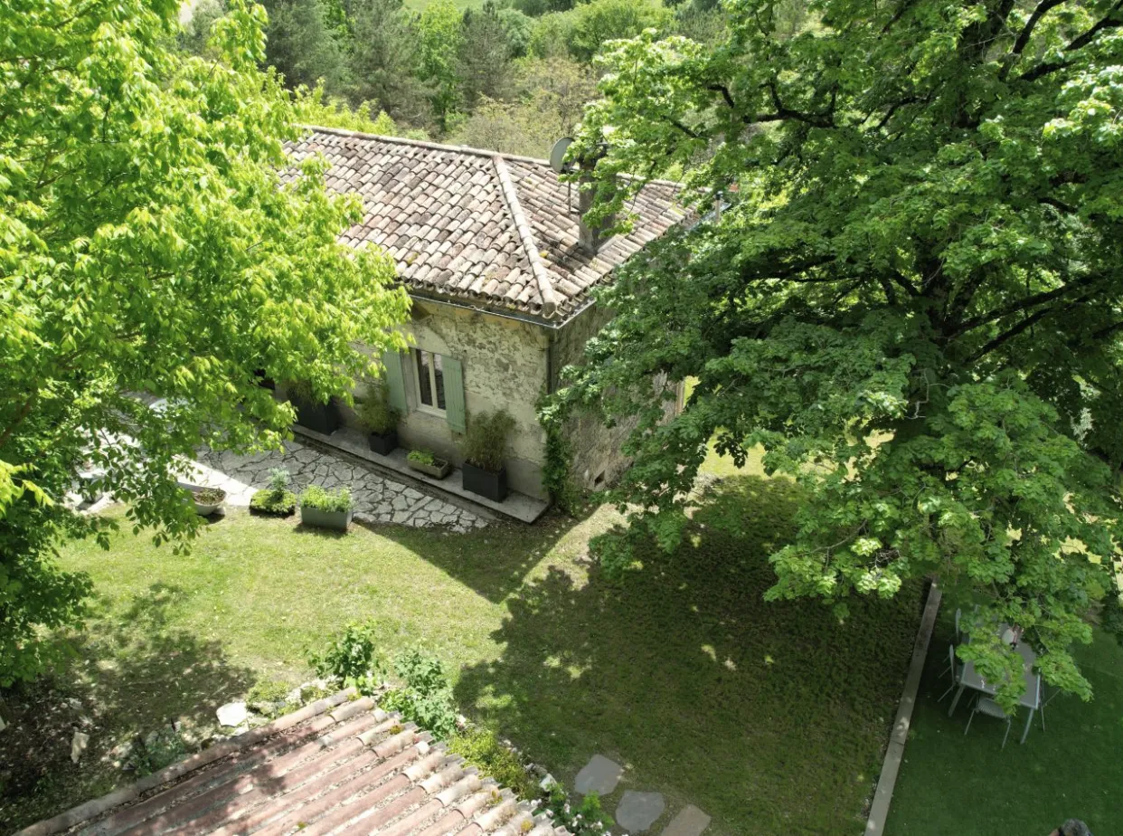 Vue aérienne du domaine de l'immersion nature, une maison en pierre entourée d'arbres près de Montauban