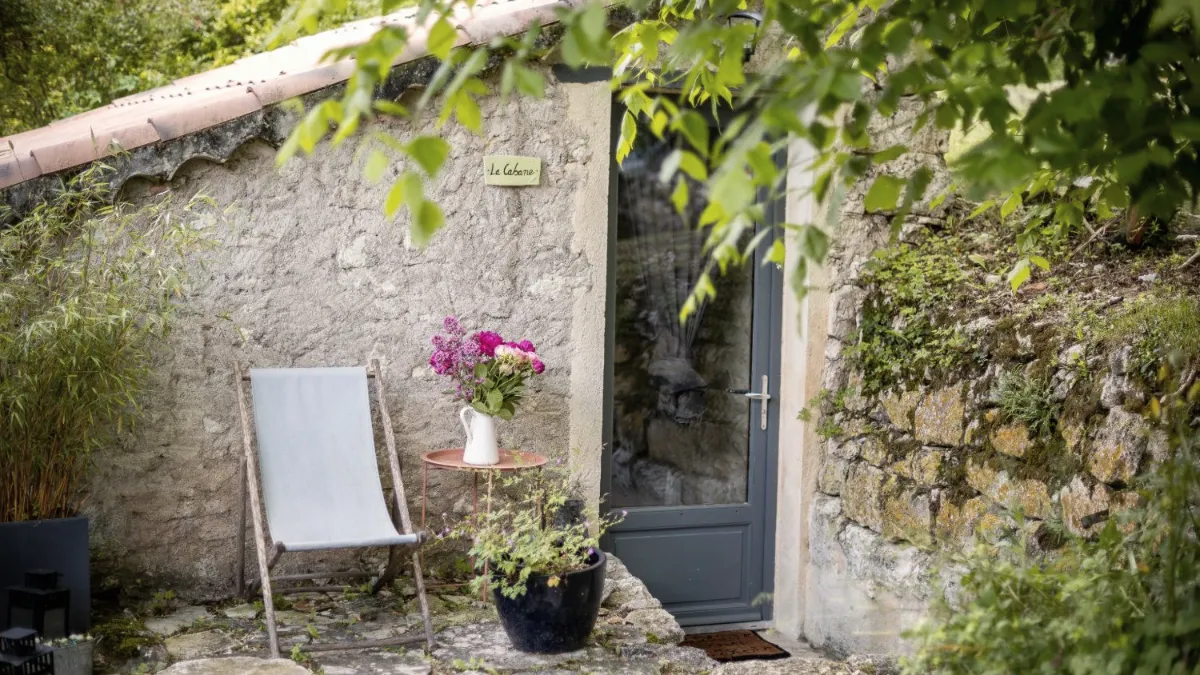 Transat et bouquet de fleurs devant La Cabane, petite maison en pierre au cœur de la nature, lieu des immersions de Frédérique Cuesta