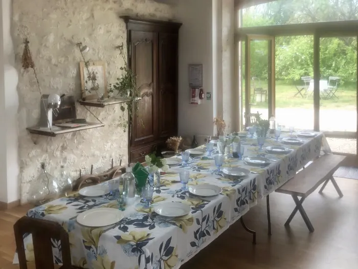Grande table dressée pour le repas, ouverte sur le jardin